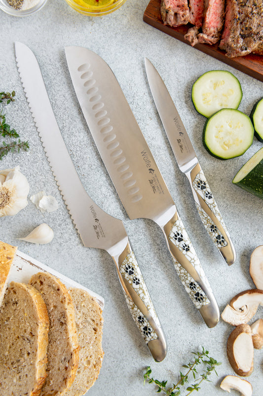 Set of knives with decorative handles on a table with bread and vegetables