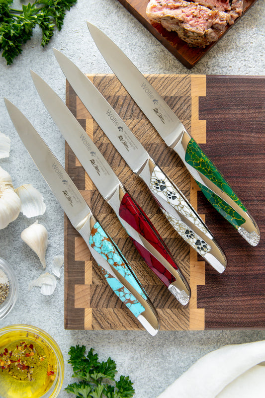 Set of knives with decorative handles on a wooden cutting board, surrounded by kitchen items.