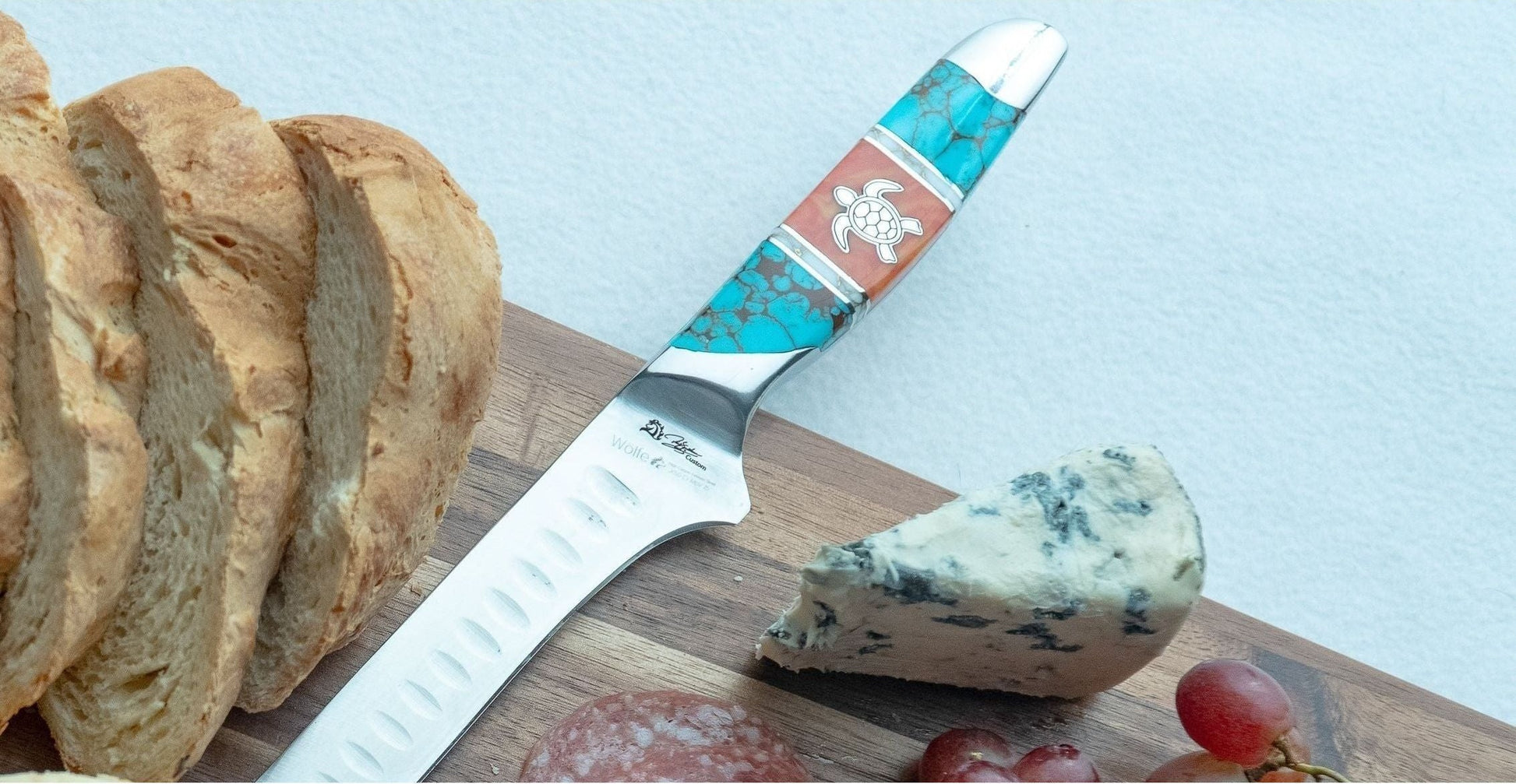 Knife with a decorative handle on a wooden board with bread and cheese.