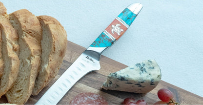 Knife with a decorative handle on a wooden board with bread and cheese.