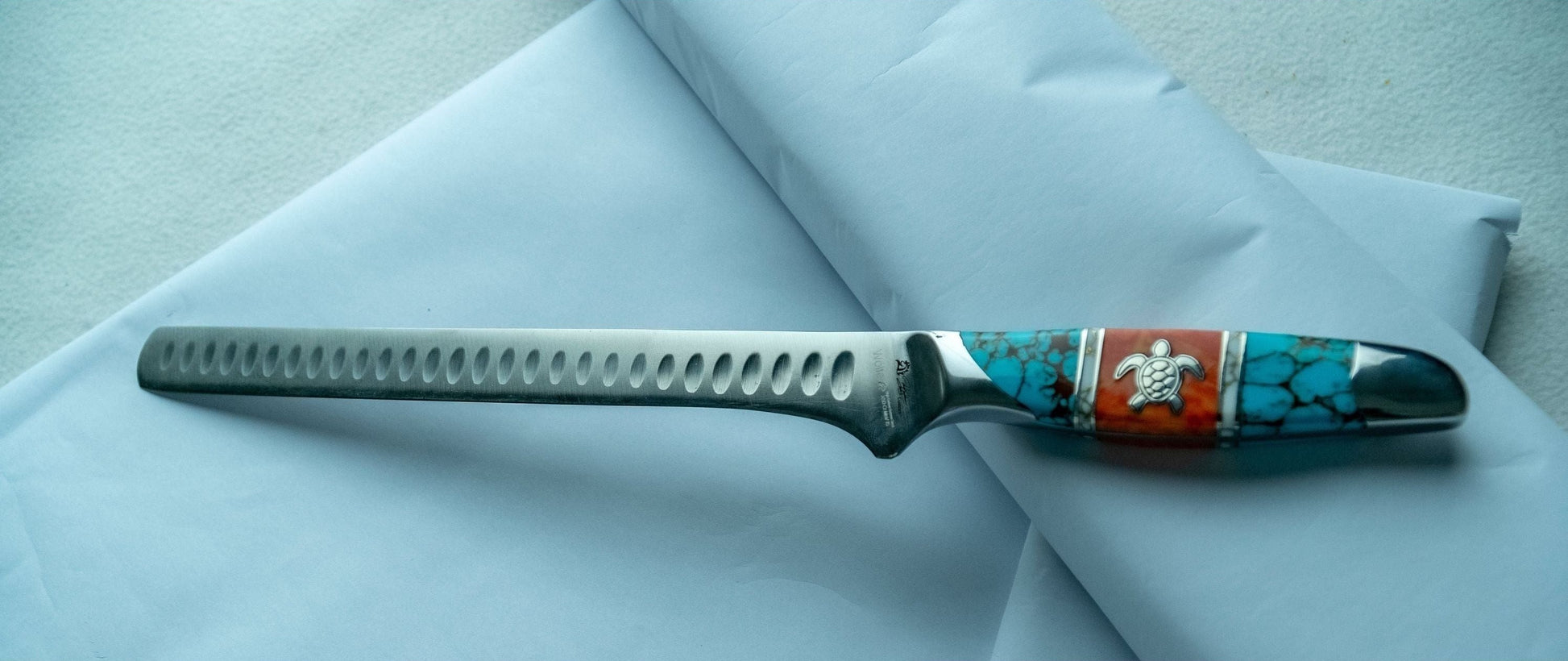 Knife with decorative handle on a light blue fabric background