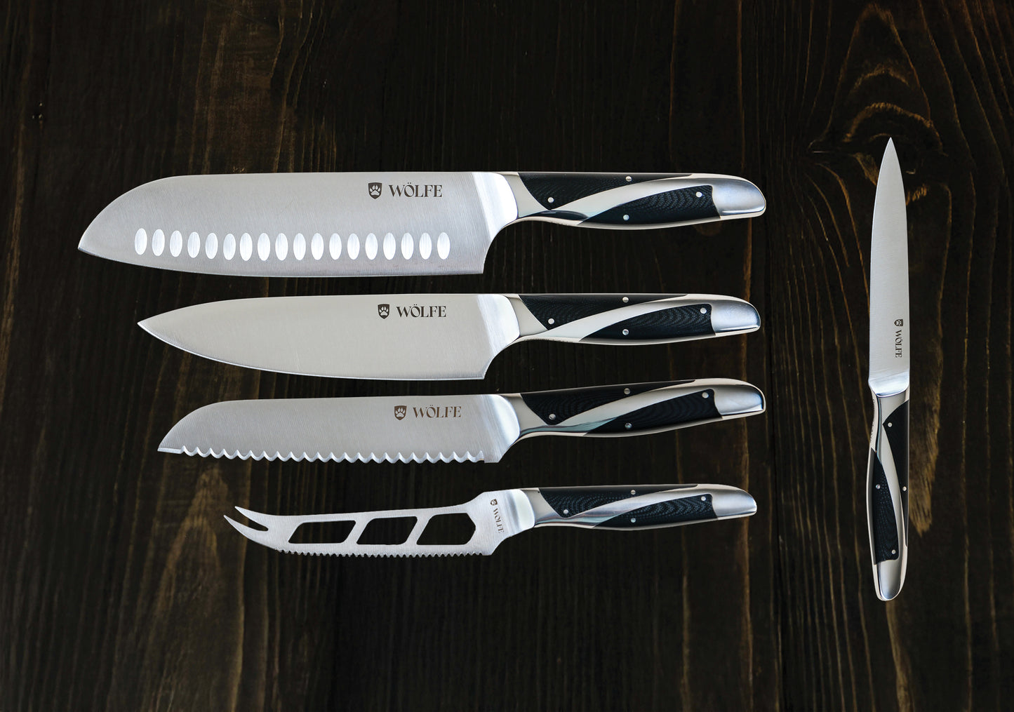 Set of knives with 'Wolfe' branding on a dark wooden surface